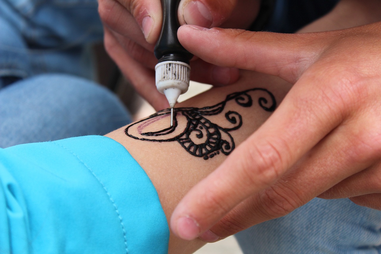 persona tatuando mano con henna negra
