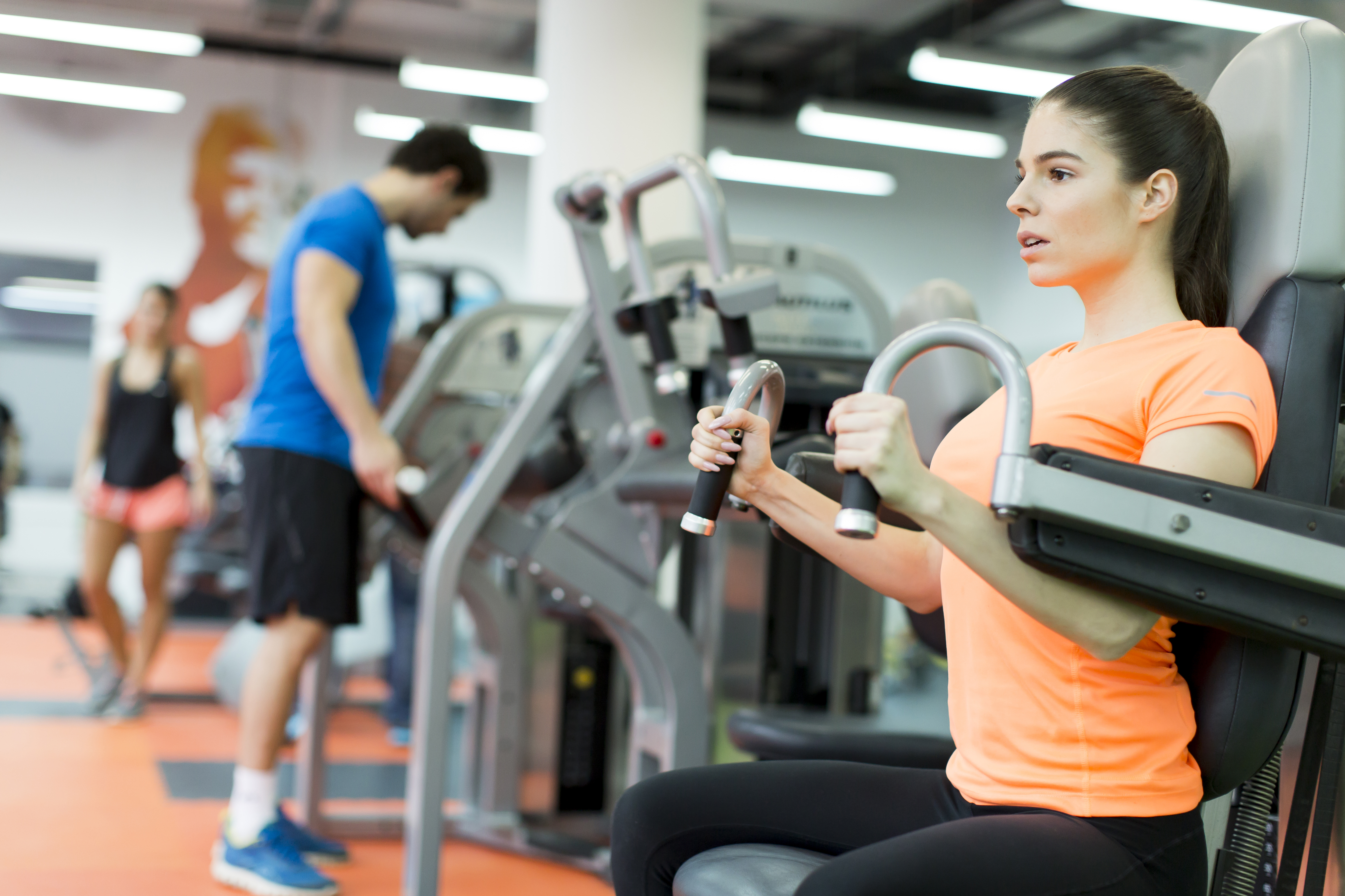 chica con maquina en gimnasio musculando brazos